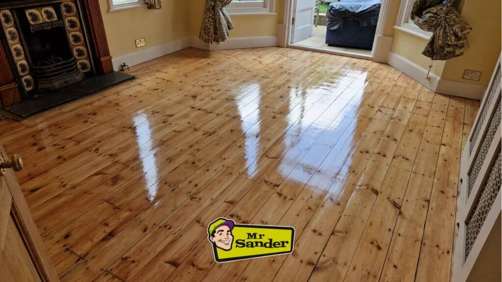 Gleaming pine wood floor after refinishing by Mr Sander® in a traditional room with a fireplace in Bulphan, UK.