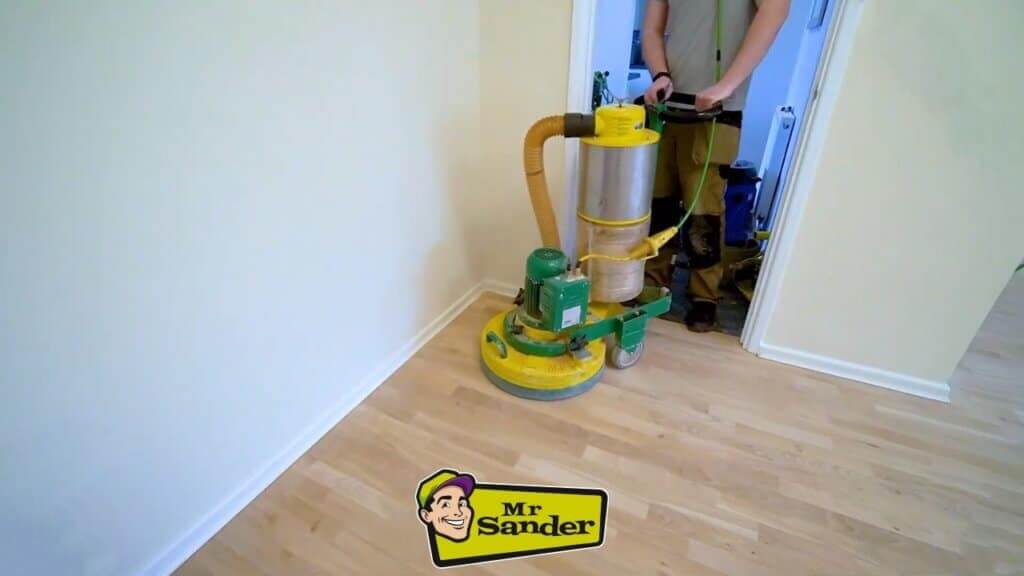 A professional from Mr Sander using a green floor sanding machine on light-colored engineered wood flooring in Bulphan, UK.