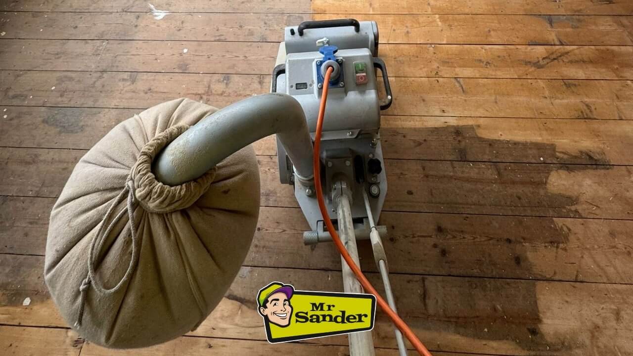 A professional floor sanding machine in action, removing the top layer of a worn and stained pine floor. The Mr Sander® logo is displayed at the bottom of the image.