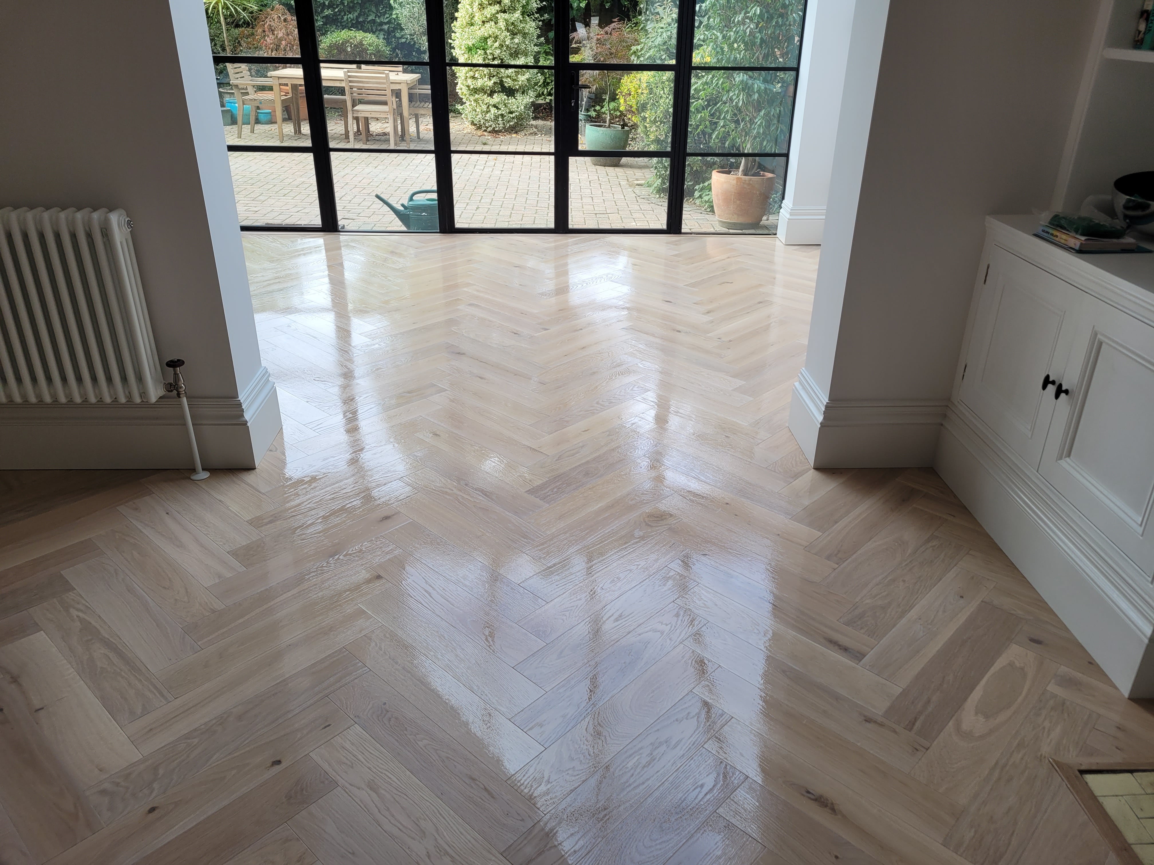 A Chevron parquet floor has been masterfully restored through sanding, buffing, and whitewashing with Bona 2K Frost, then treated with two coats of Traffic HD 10% sheen matte lacquer, resulting in a stunning, long-lasting finish.