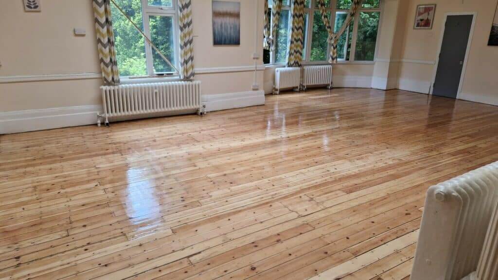 A beautifully polished wooden floor in a spacious room with large windows in Clapham Junction, UK. Mr Sander® provides expert floor sanding and refinishing services in this area, ensuring floors look pristine and well-maintained.
