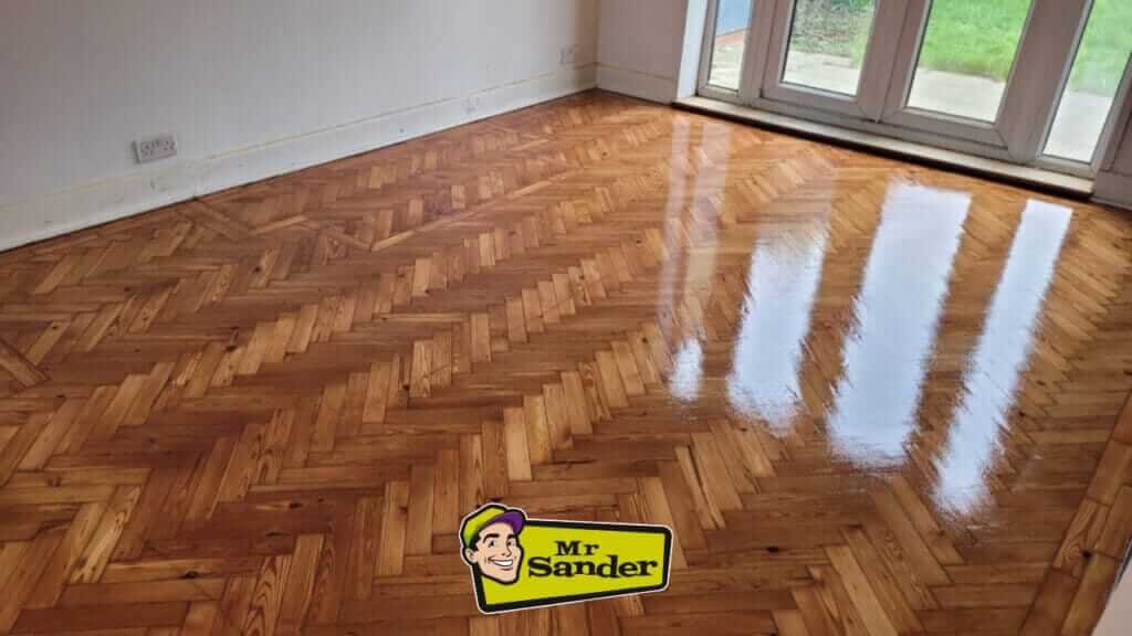A beautifully restored herringbone parquet wood floor in a UK home. The floor is light-colored, likely oak