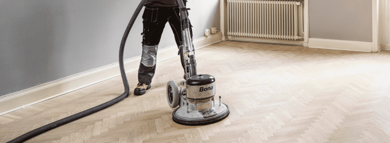 Mr Sander® skillfully sanding a herringbone floor using the powerful 2.2 kW Bona belt sander. The 230V, 50Hz machine, sized 200x750 mm, creates stunning results while the HEPA-filtered dust extraction system ensures cleanliness and efficiency.