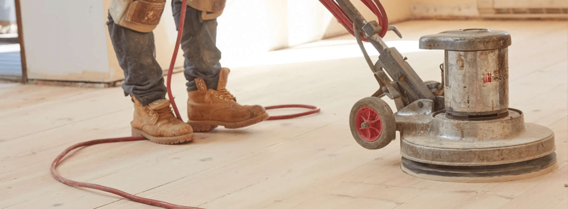A floor sanding professional using a Bona FlexiSand 1.9, a powerful buffer sander with a 407 mm diameter. The sander is connected to a dust extraction system with a HEPA filter, ensuring efficient and thorough sanding. The setup operates at 230 V and 50 Hz/60 Hz in New Cross, SE14.