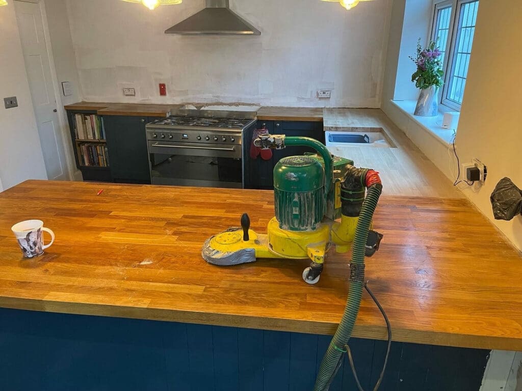Wooden kitchen counter with a floor sander and a cup of tea on top.