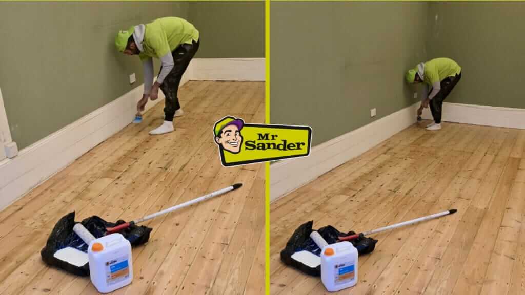 A professional floor refinishing expert from Mr Sander® applies finishing touches to a wooden floor using a brush near the baseboard. The room has green walls, and wooden planks are being sanded and refinished. Tools such as a paint roller, handle, and a container of finishing solution are placed nearby.