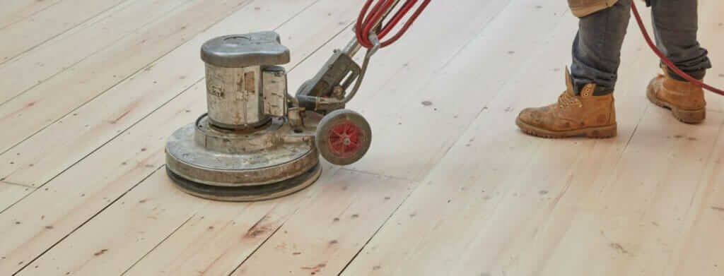 A professional from Mr Sander® sanding a floor in a living room in, UK using the Bona FlexiSand 1.9 (AMO310002) buffer. The machine features a 1.9 kW motor, 230 V voltage, 50 Hz frequency, 407 mm disc diameter, 147 rpm abrasive disc speed, and weighs 50 kg.