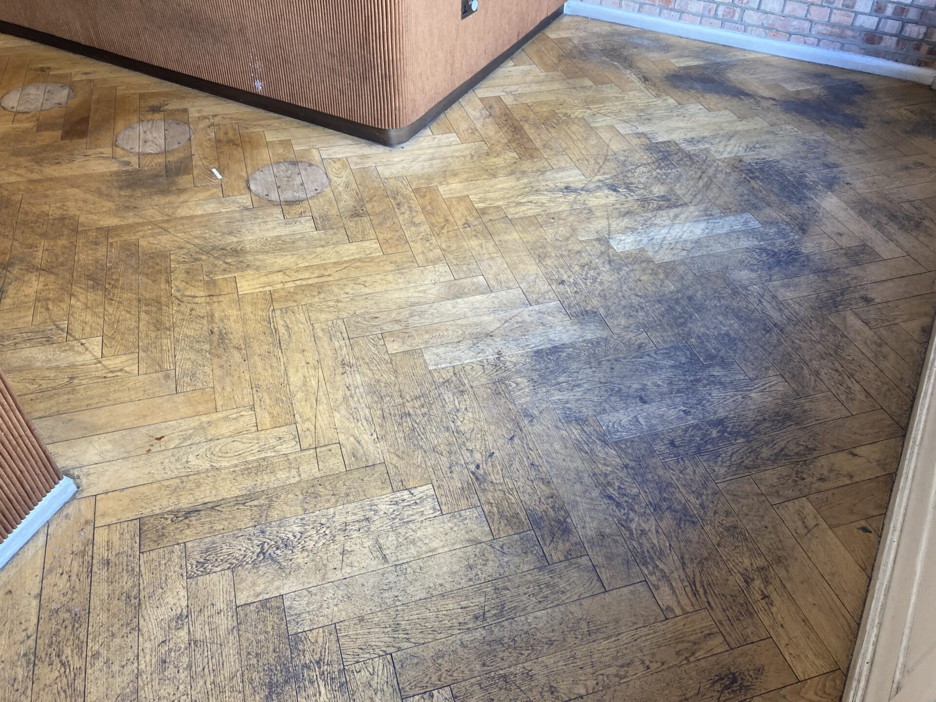 Heavily worn oak herringbone floor in a UK restaurant, displaying scratches and discolouration before refinishing.