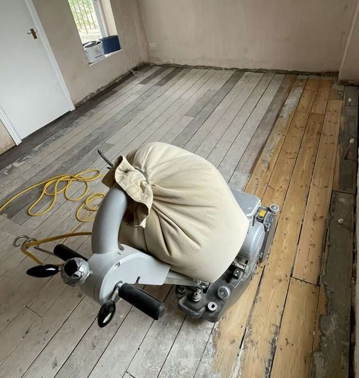 A professional from Mr Sander® is sanding a living room floor in Blackbushe, UK, using a Frank Cobra Belt Sander. The high-powered, dust-free machine weighs 78kg and features a 2500W motor, 2100rpm sanding speed, and 200x750 endless belt. The Frank Cobra offers quick belt changes, integrated DCS for 99.99% dust extraction, featherlite clutch control, and automatic belt adjustment. Ideal for professional sanding and stripping of all wooden floors, including parquet.