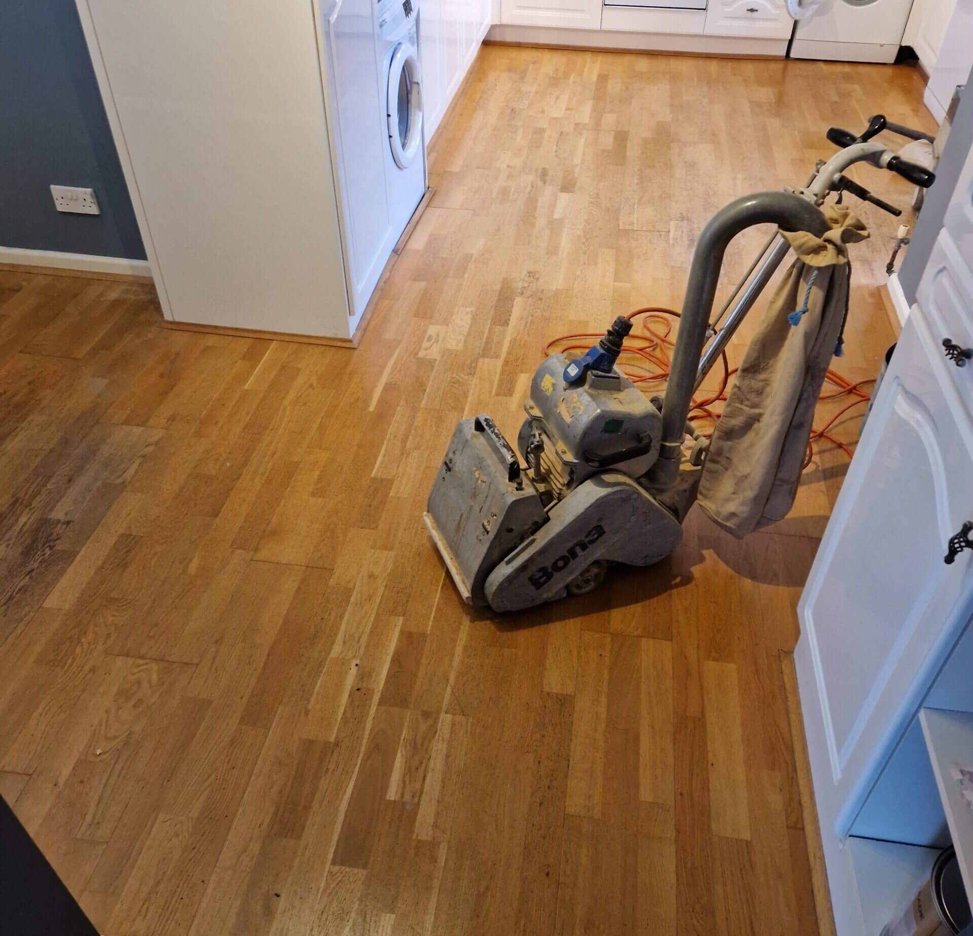 Bona floor sanding machine in a residential kitchen, highlighting the process for Floor Sanding and Color Choices.