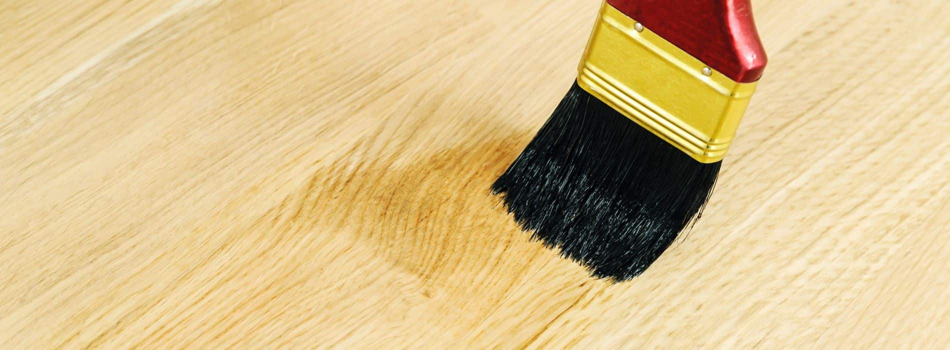 A red and black brush sitting on top of a wooden floor.