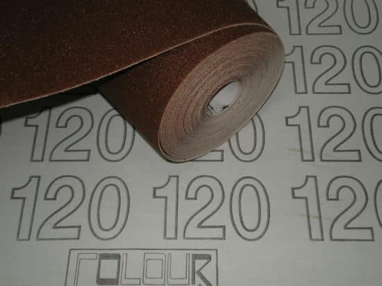 A roll of brown 120-grit sandpaper lying on a background with the number 120 repeatedly printed on it.