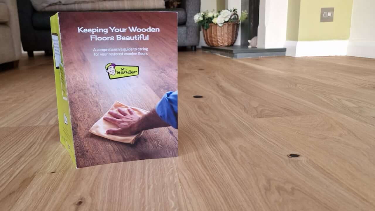 A guidebook titled 'Keeping Your Wooden Floors Beautiful' displayed on a freshly restored wooden floor, showcasing Mr Sander®'s expertise in floor sanding and maintenance.