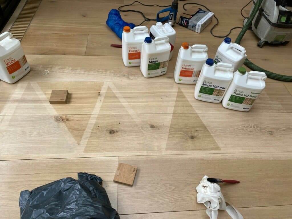Various Bona finish products placed on a newly sanded wooden floor, with tools and equipment in the background.