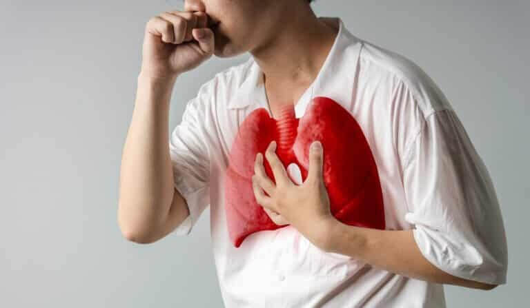 A man in a white shirt coughing while clutching his chest, with his lungs highlighted in red, illustrating the question “Do lungs clean themselves of sawdust?”