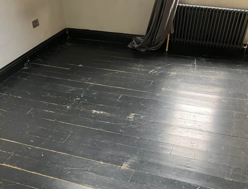  A dark, worn wooden floor with visible scratches and imperfections.