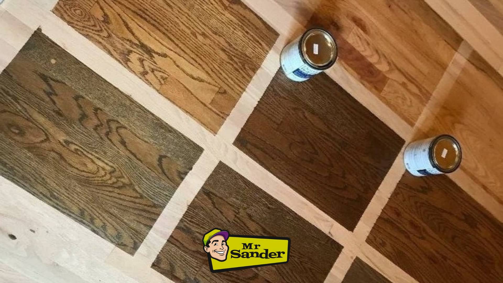 A wooden floor with multiple stain samples applied in a grid pattern, showing different color options for refinishing. Two cans of wood stain are placed on the floor, and the Mr Sander® logo is visible at the bottom center of the image.