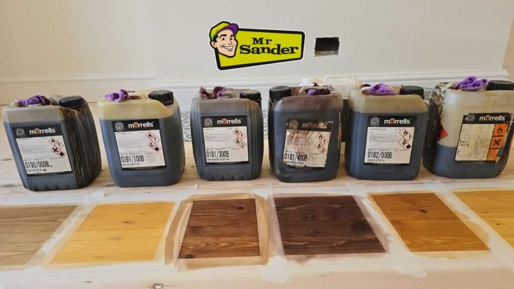 Various containers of Morrells wood finishes and stains displayed alongside wooden samples showcasing different finish shades and effects.