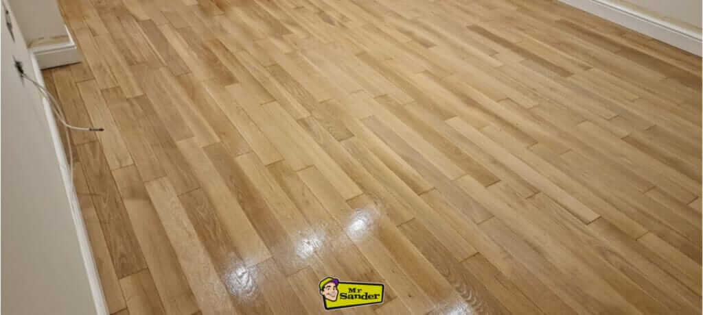 A beautifully refinished light oak hardwood floor with a polished, smooth surface, showcasing expert craftsmanship.