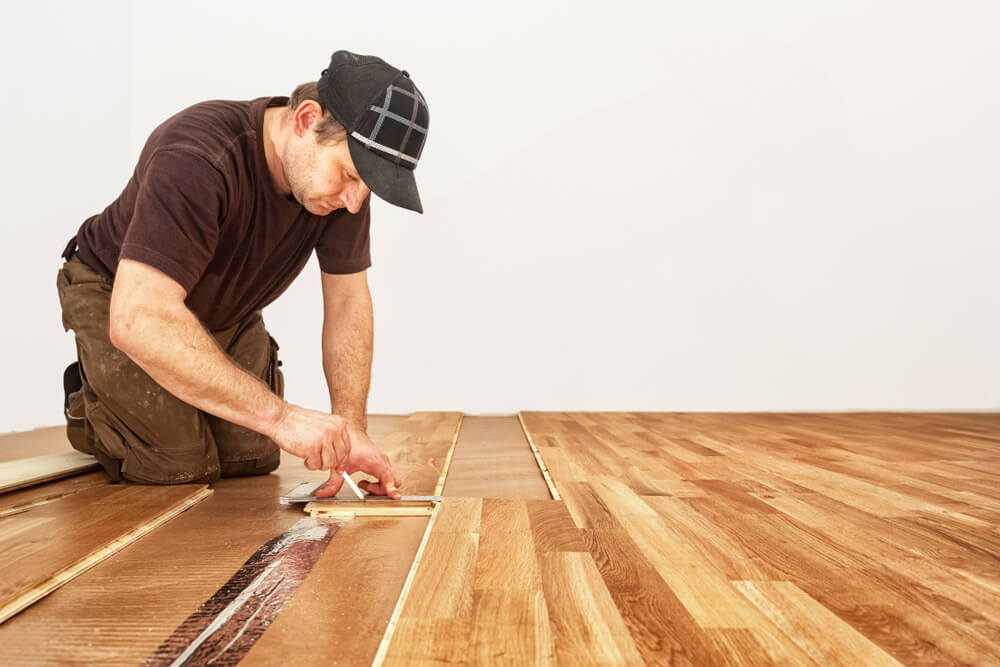 A professional from Mr Sander in London performing an Engineered Floor Installation on hands and knees