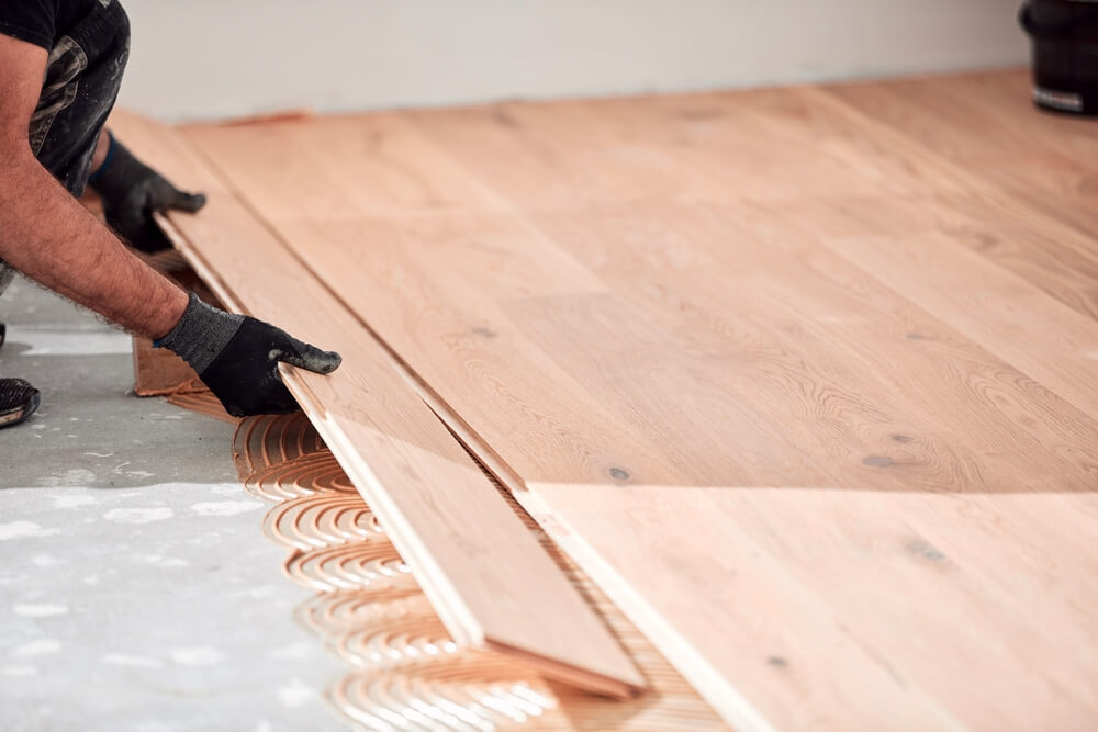 Professional installer placing engineered oak planks onto adhesive, highlighting the glue-down wood floor installation method.