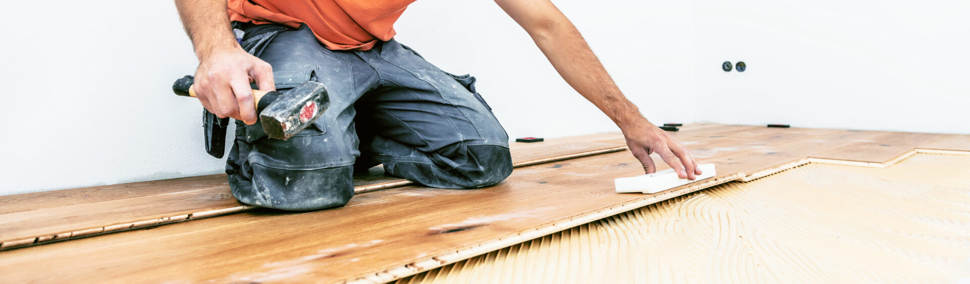 Engineered Wood Floor Installation – skilled fitter taps engineered oak planks into full-spread adhesive for a flawless finish