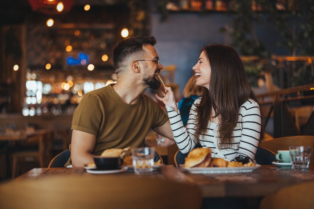 A smiling couple enjoying a meal in a UK restaurant featuring newly refinished hardwood floors for a warm, welcoming atmosphere.