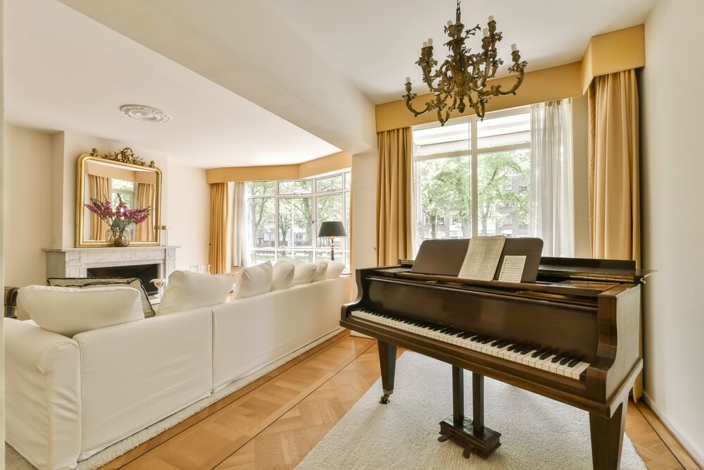 A grand piano placed on a thick area rug atop a hardwood floor, providing a layer of protection.