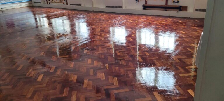 High-gloss parquet floor in a large hall, showcasing the professional results of Commercial Floor Sanding.