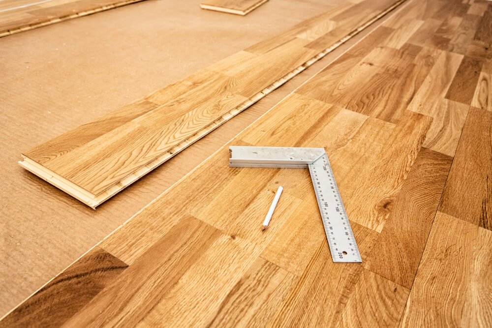 Oak planks being carefully aligned over an underlayment, illustrating the floating method for a wood floor installation.