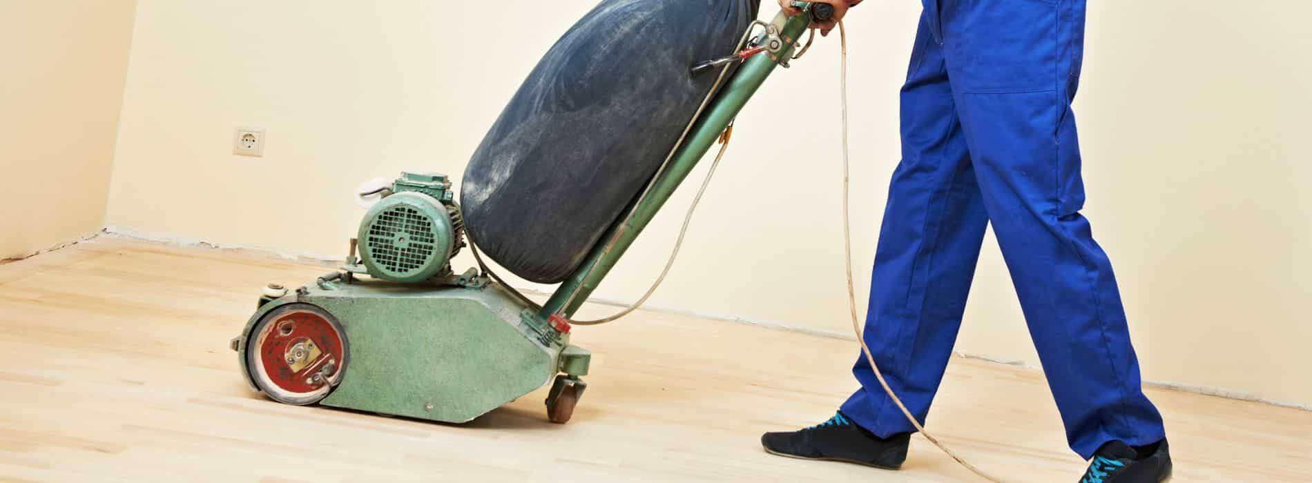 An individual operates a floor sanding machine with a 551mm dust sheet and 60-grit sandpaper, expertly restoring a 90mm solid oak strip floor in RG20.
