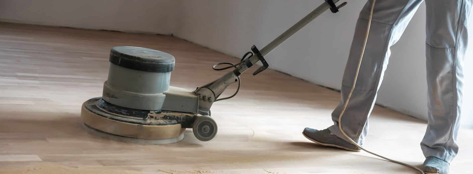 A team of professionals bring out the luster in a parquet floor, utilizing a powerful 240v polishing machine with a 407mm driving plate and a 60grit screen to achieve a flawless finish.