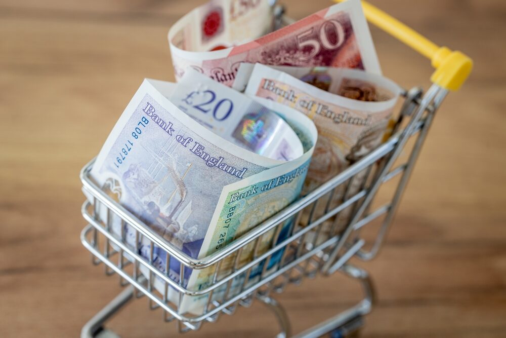 Mini shopping trolley overflowing with rolled UK banknotes symbolising the hidden costs of floor sanding machine hire.
