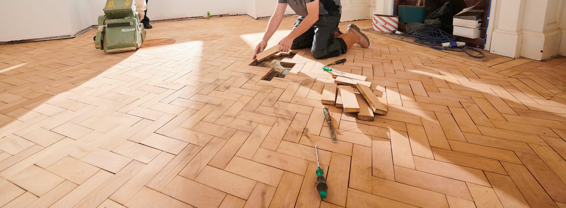 a man is working on a wooden floor.