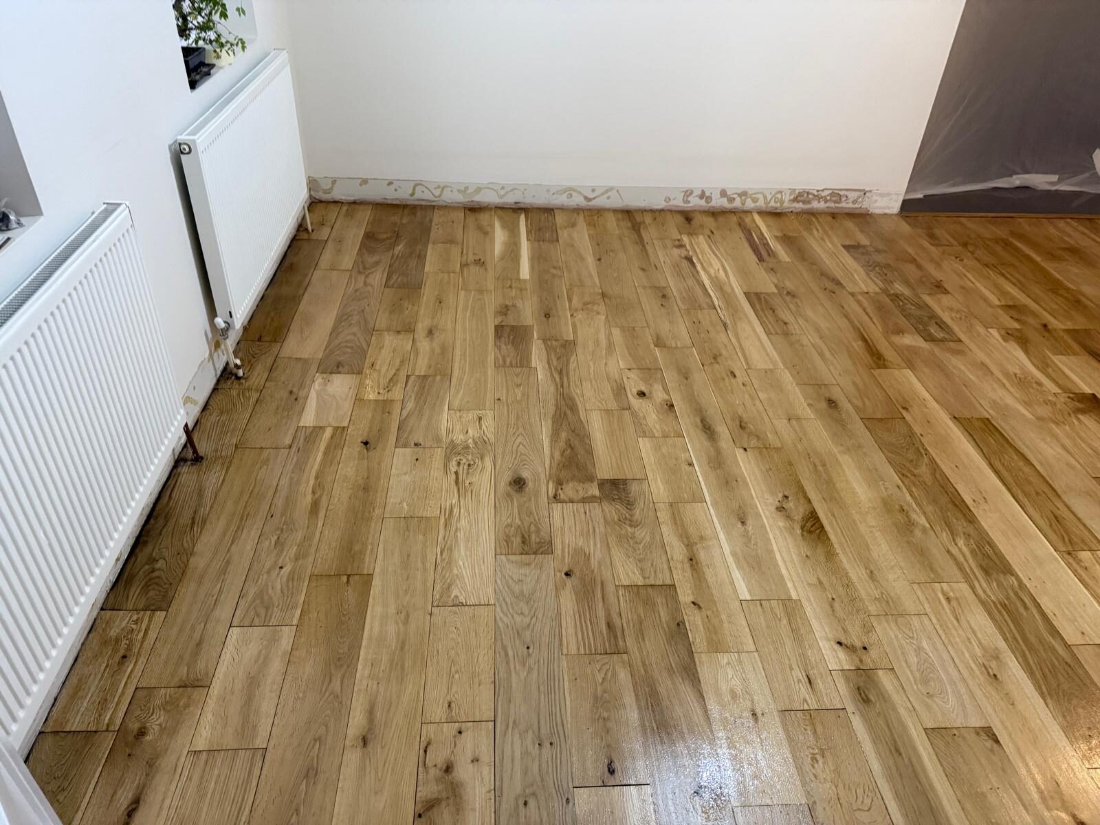 Floor Sanding and Oil Finishes – newly oiled light-oak boards curing in a UK dining room, radiators and masked skirting visible