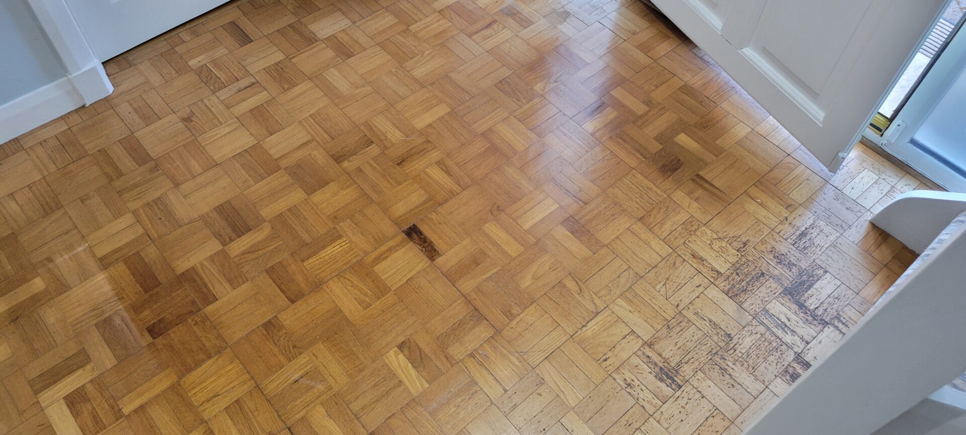 Worn oak parquet floor awaiting Floor Sanding and Restoration, showing scratches and water stains near the doorway.