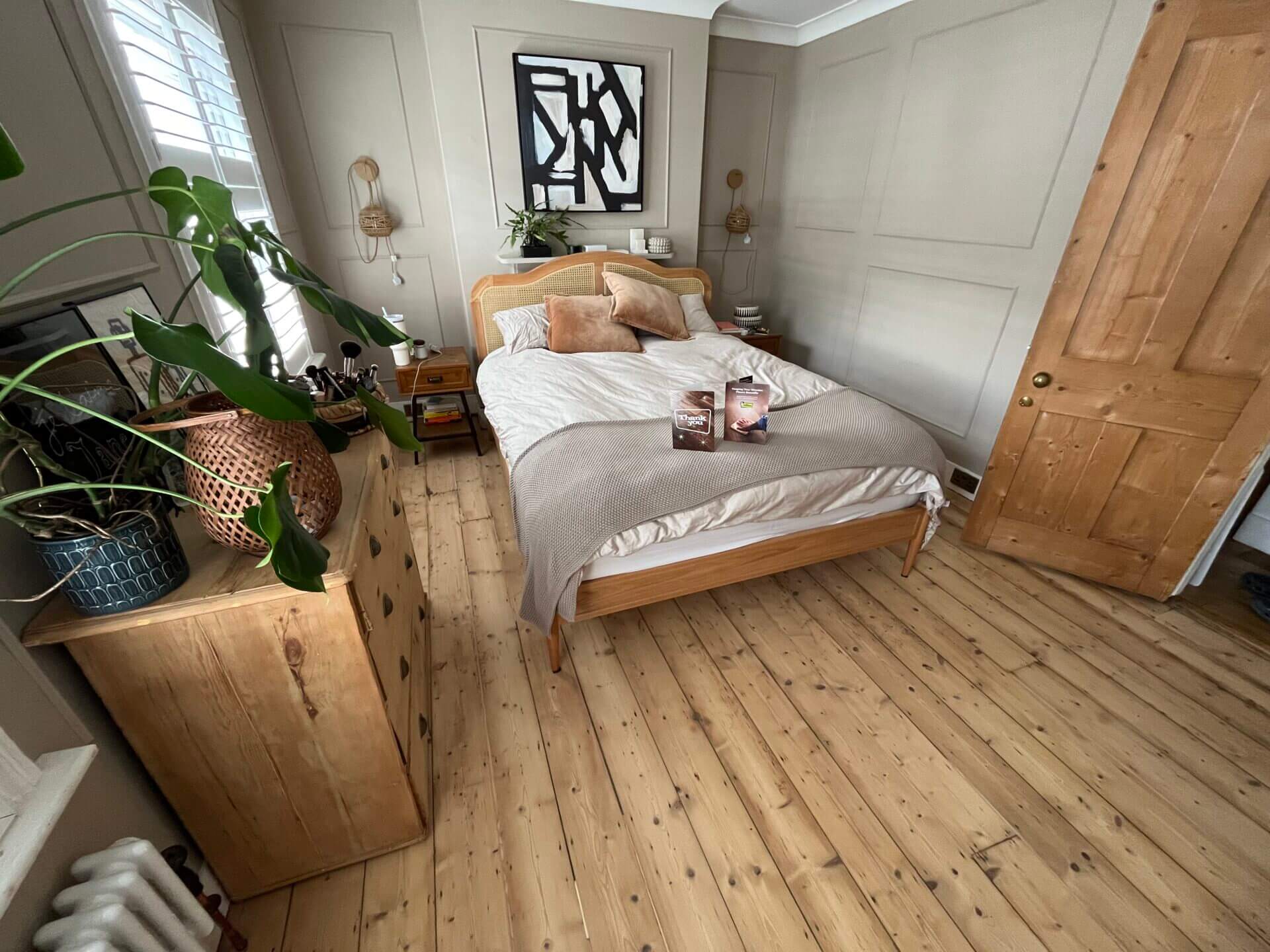 A freshly sanded wooden bedroom floor, complete with neutral décor and natural wooden furniture, demonstrating the transformative impact of professional floor sanding for bedrooms.