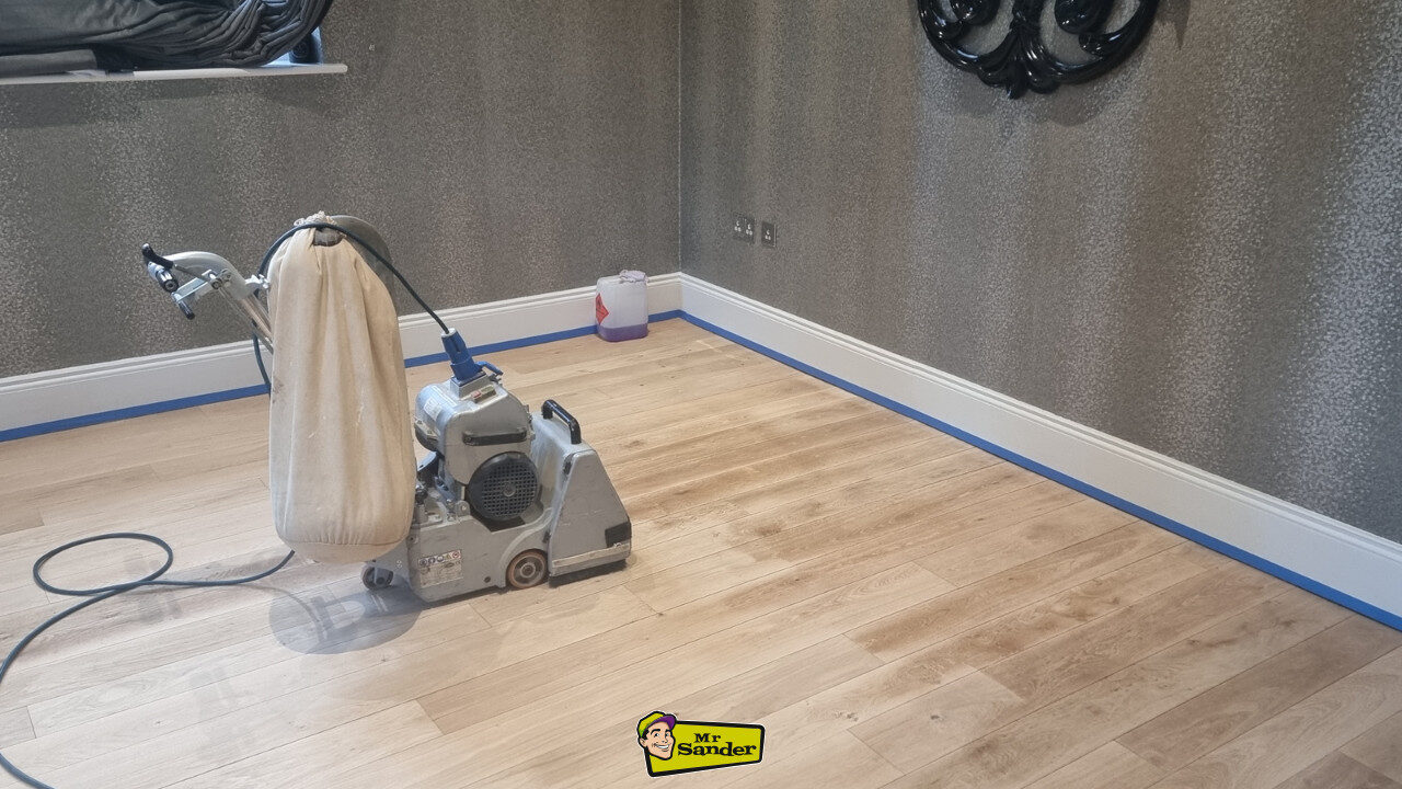 A professional sanding machine on a partially refinished wooden floor, demonstrating the importance of Floor Sanding in Schools and Hospitals for a cleaner, safer surface.