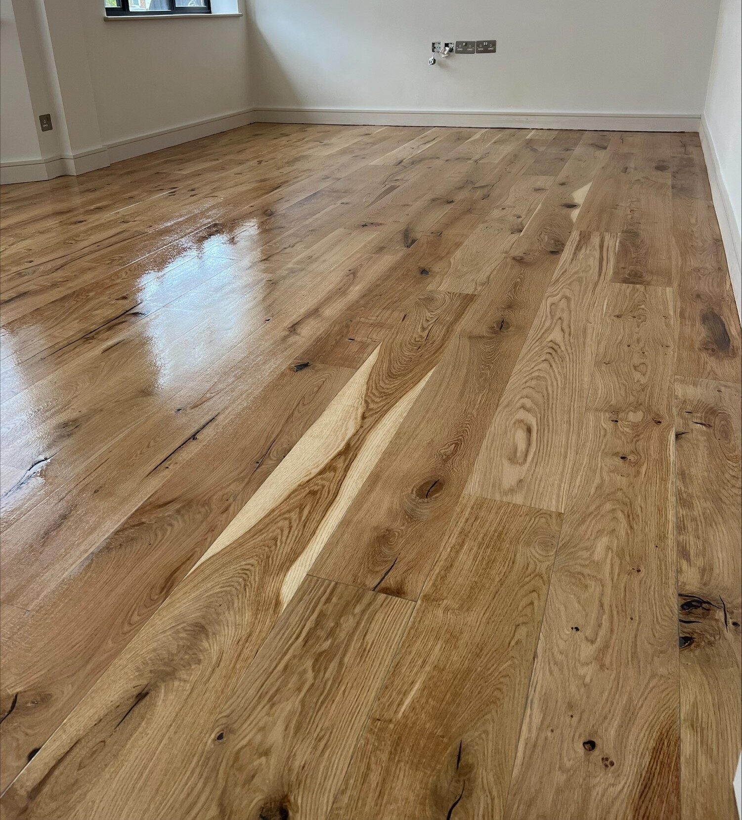 Engineered Wood Floor Installation – newly installed, lacquered engineered oak floorboards gleam in a bright, empty room