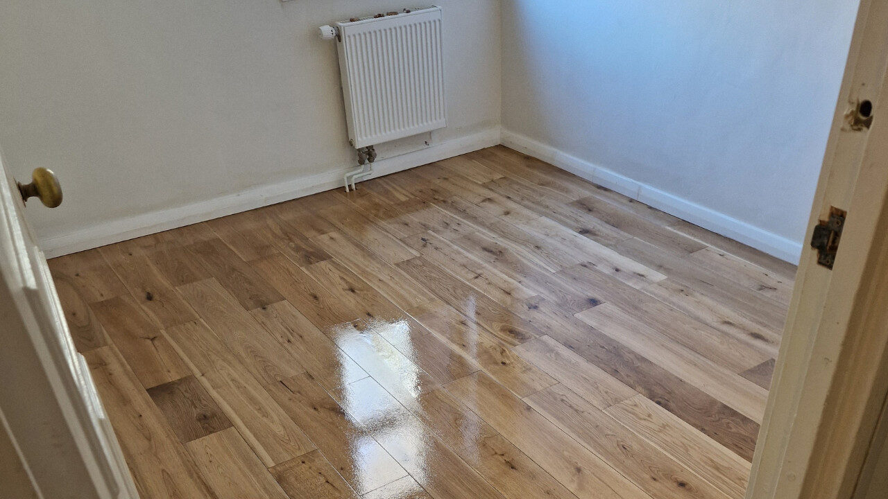 Engineered Wood Floor Installation – freshly restored engineered oak floor with a high-gloss lacquer finish in a compact bedroom