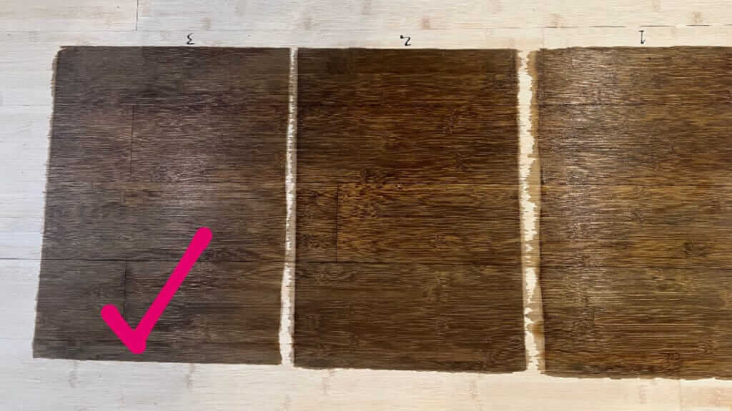 Three wood samples stained with different shades of brown. A checkmark is next to the middle sample.