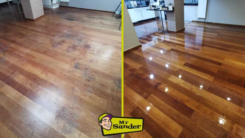 A before and after comparison of a wooden floor restoration. The left side shows a worn-out, stained floor with visible patches and dullness. The right side displays the same floor after sanding and refinishing, now gleaming with a smooth, polished surface and rich wood tones, reflecting light. The room features modern open-plan elements, with a kitchen area in the background.