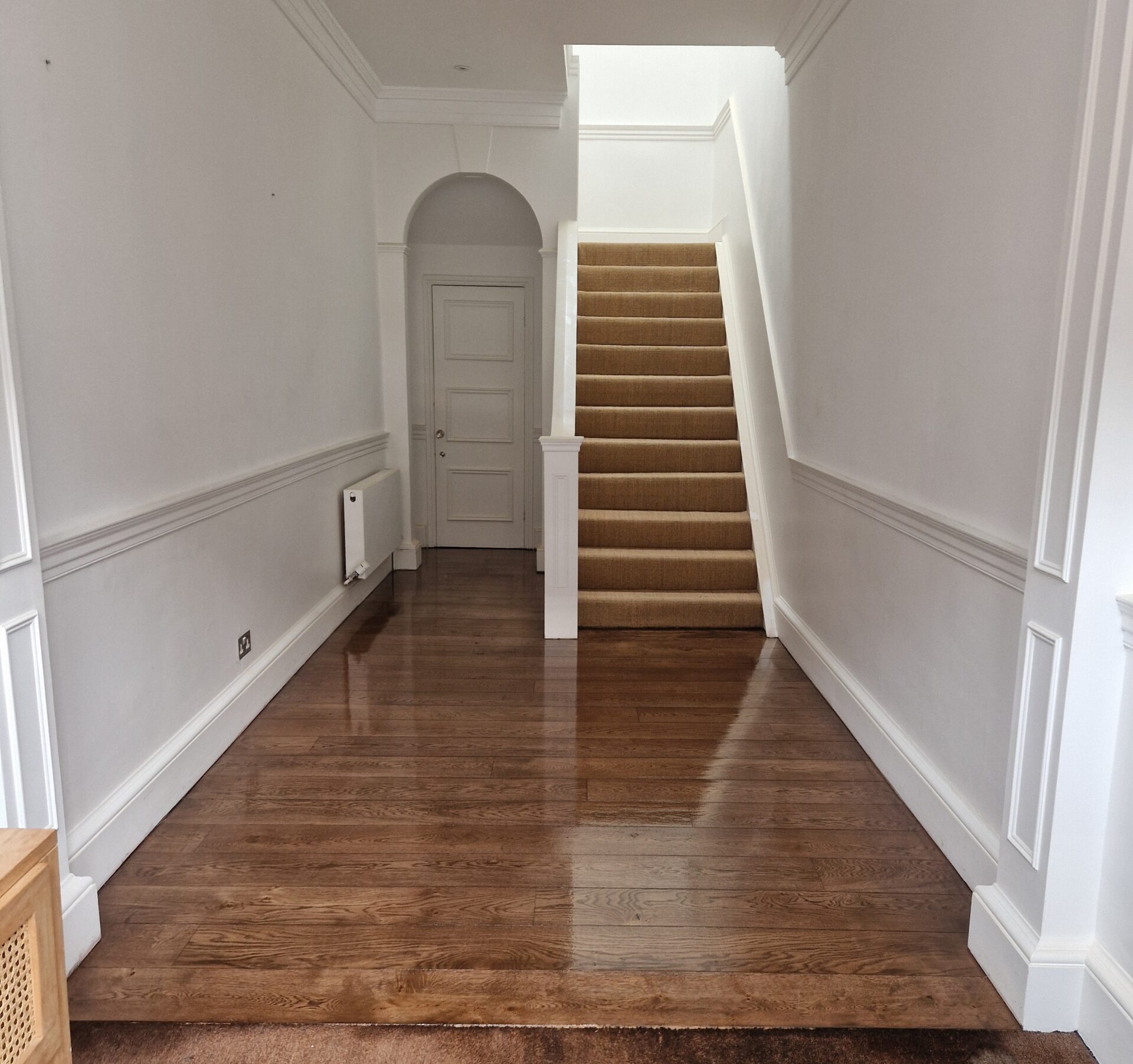 Bright entrance hallway showcasing a freshly refinished oak floor, leading up to a carpeted staircase, illustrating the impact of Floor Sanding in Modern Homes by Mr Sander®.