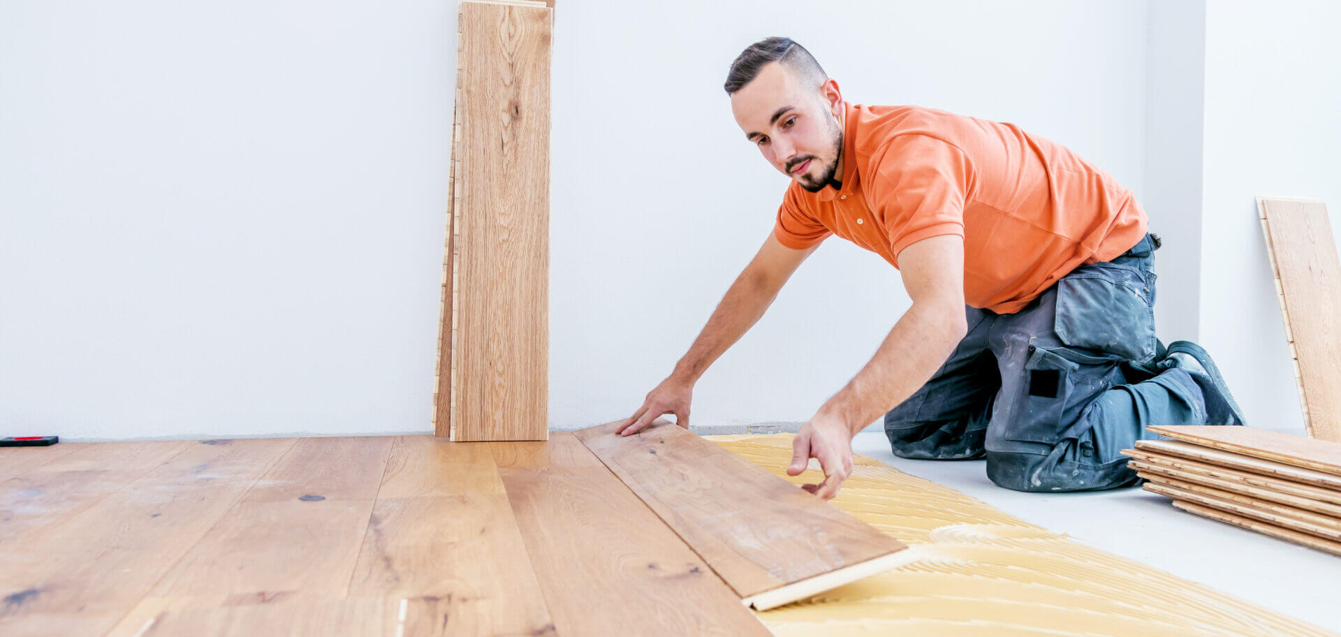 Professional fitter positioning wooden planks on the subfloor during a Hardwood Floor Fitting project.