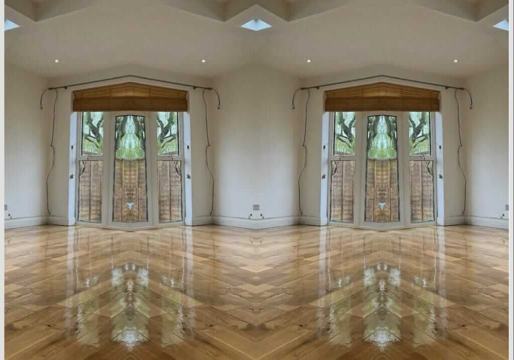 A bright room featuring a high-gloss finished parquet floor. The polished floor reflects light, creating a mirror-like effect. The room includes large French doors with wooden blinds, allowing natural light to flood in. The minimalistic decor highlights the elegant transformation of the wooden flooring.