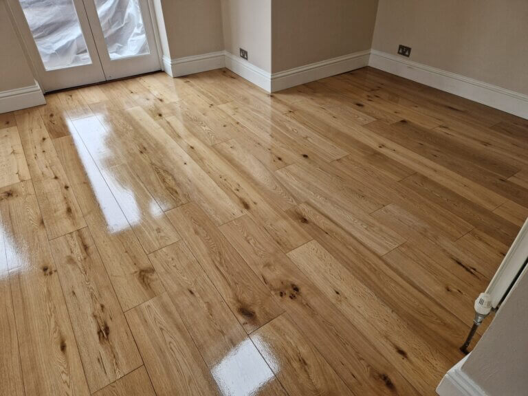 A newly installed, high-gloss oak floor in a bright room with French doors, demonstrating the polished outcome of Solid Wood Floor Fitting.