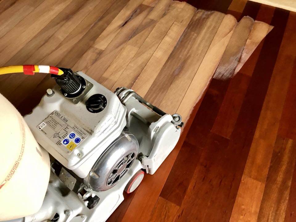 A man from Mr Sander® is sanding an oak floor in a living room in Crossness, UK, using a Bona Belt UX (AMK173100) professional belt sander. The machine specifications include a motor power of 2.2 kW, voltage of 230 V, frequency of 50 Hz, sanding belt size of 200x750 mm, drum width of 200 mm, and weight of 85 kg.