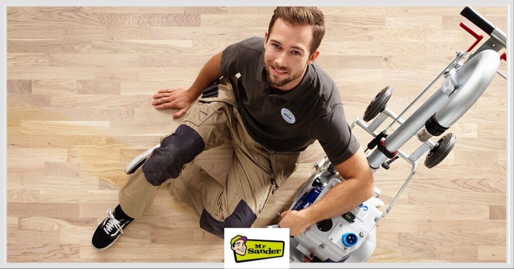 Mr Sander professional smiling next to a modern floor sanding machine on a perfectly sanded light oak wooden floor in Loughton.