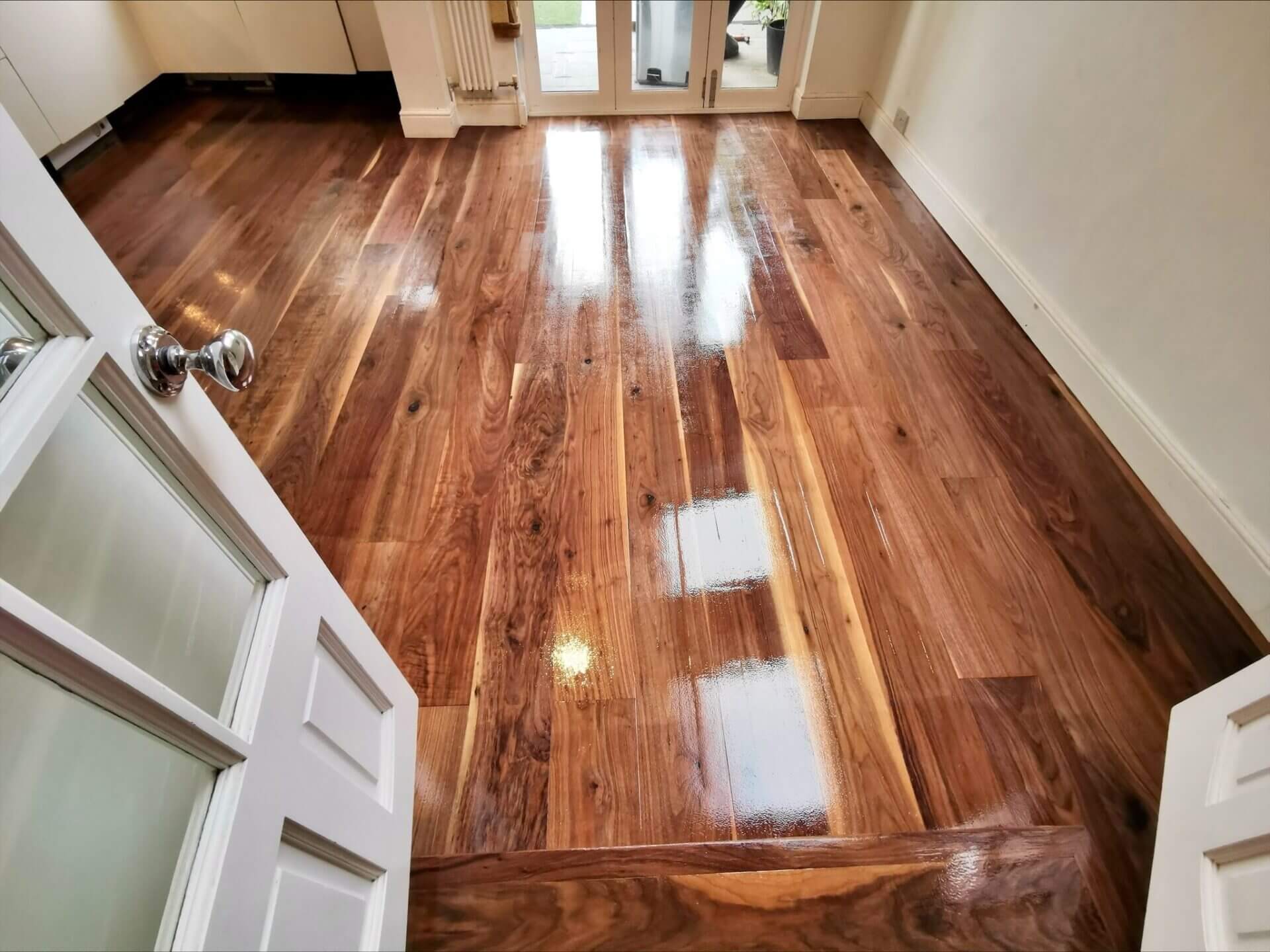 A newly installed walnut wood floor with a glossy, reflective finish, showcasing expert North London Floor Fitting craftsmanship.