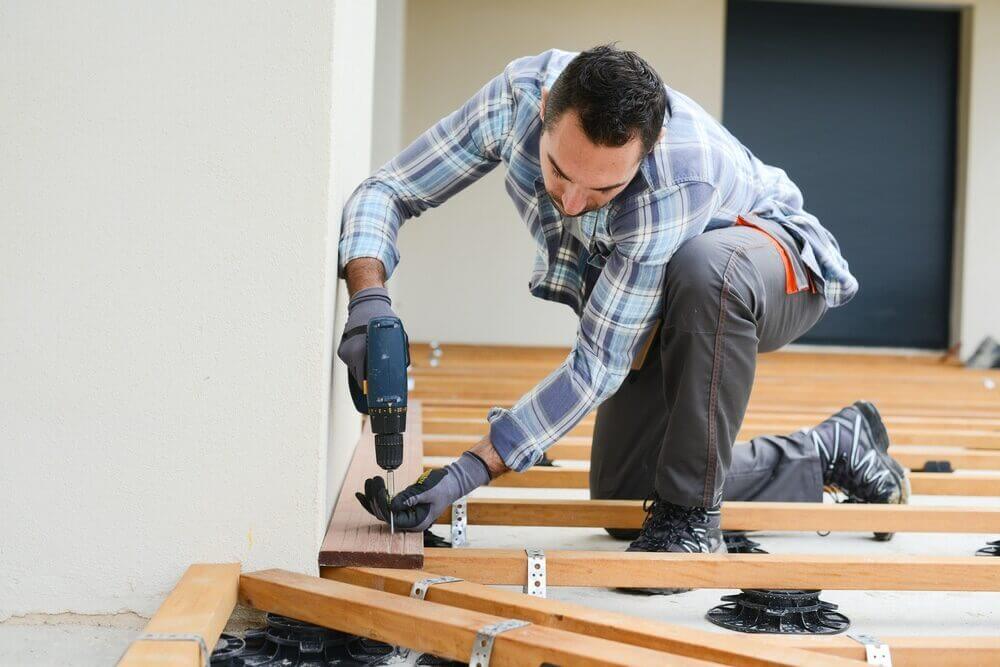 A professional floor fitter drilling wooden boards during a subfloor installation as part of a North London Floor Fitting service.